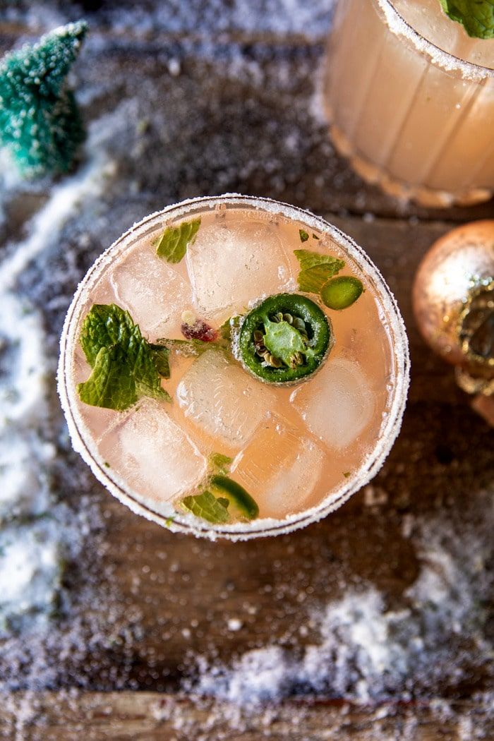 two glasses filled with drinks sitting on top of a wooden table next to christmas decorations