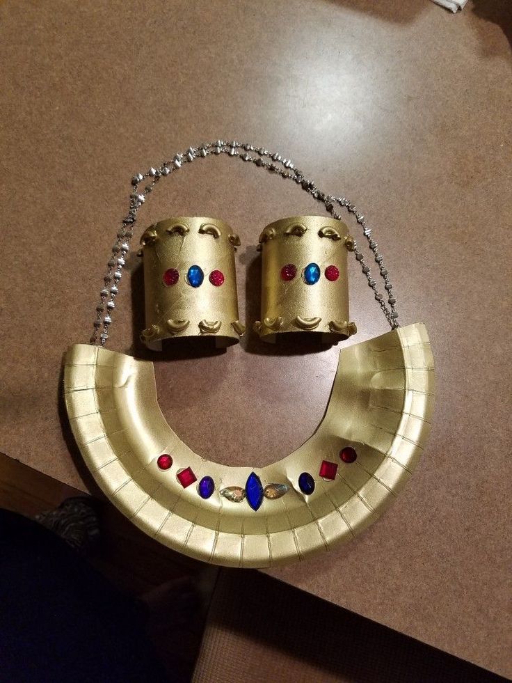 a gold necklace with two bells attached to it on top of a table next to a chain