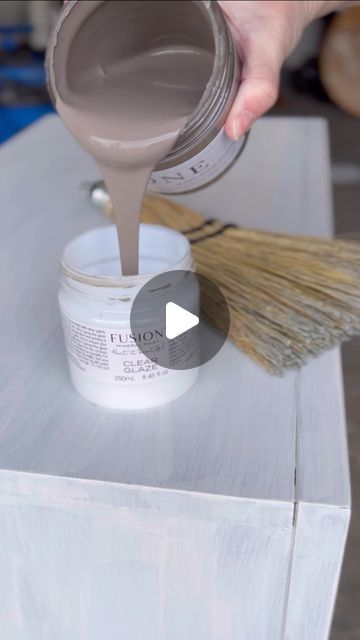 someone is painting the top of a white table with brown paint and a wooden brush