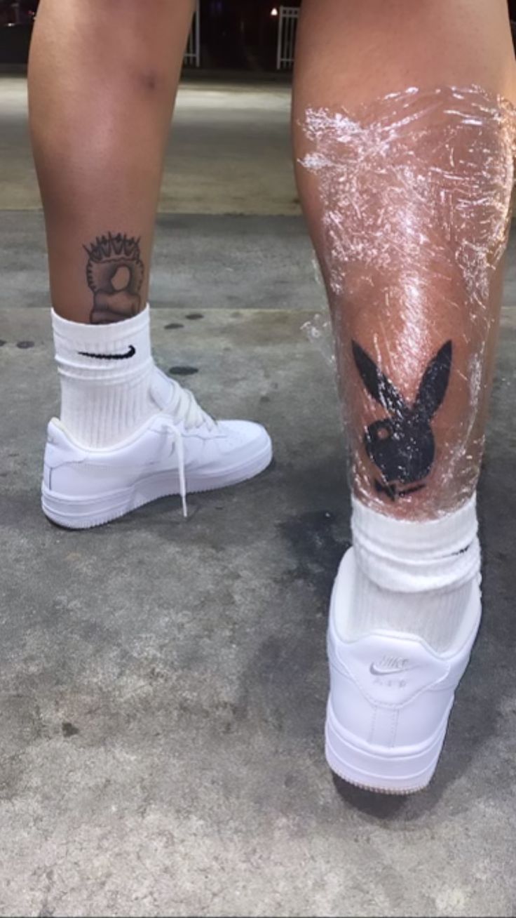 the legs and ankles of a person with tattoos on them, both wearing white tennis shoes