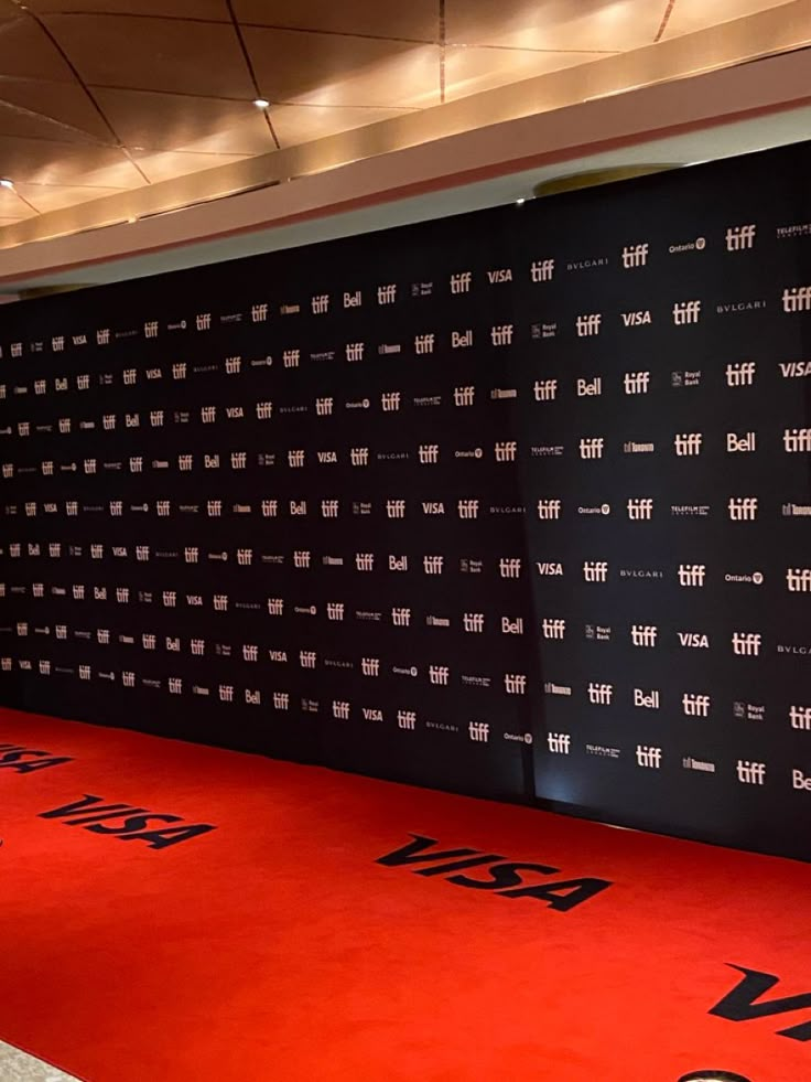 a red carpet with black and white writing on it in front of a large wall