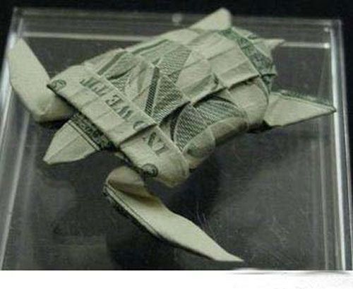 an origami fish made out of one dollar bill in a clear plastic case