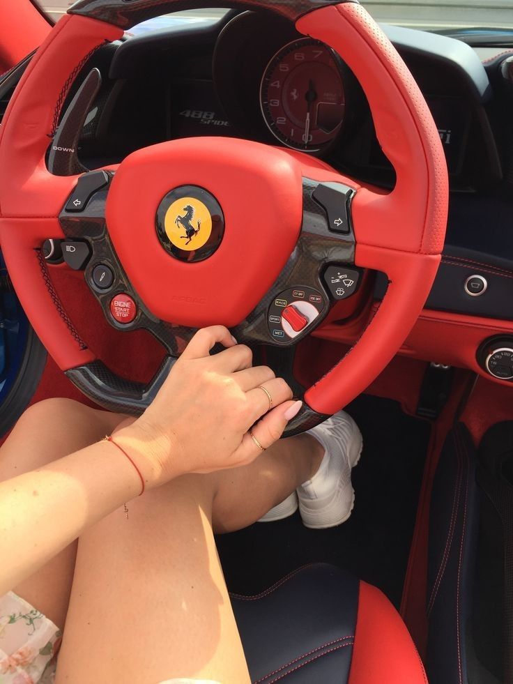 a woman is sitting in the driver's seat of a sports car with her hands on the steering wheel