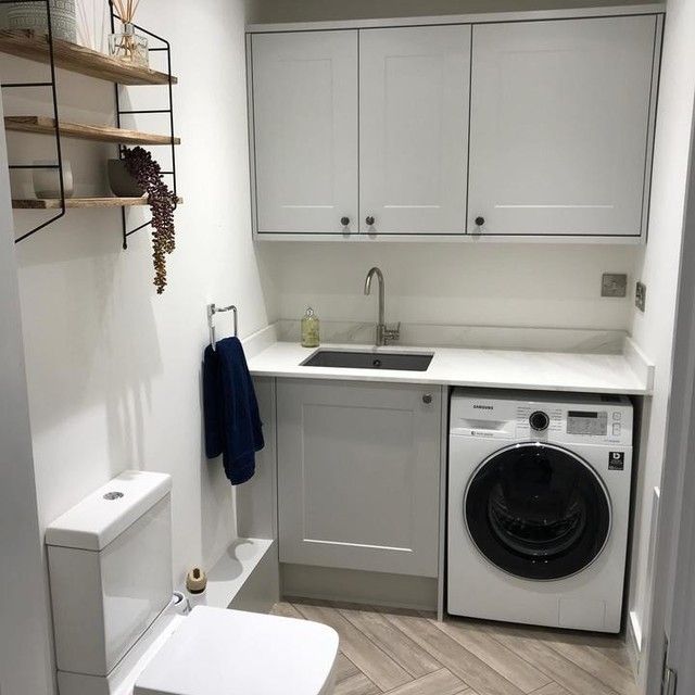 a washer and dryer in a small room with white cabinets on the walls