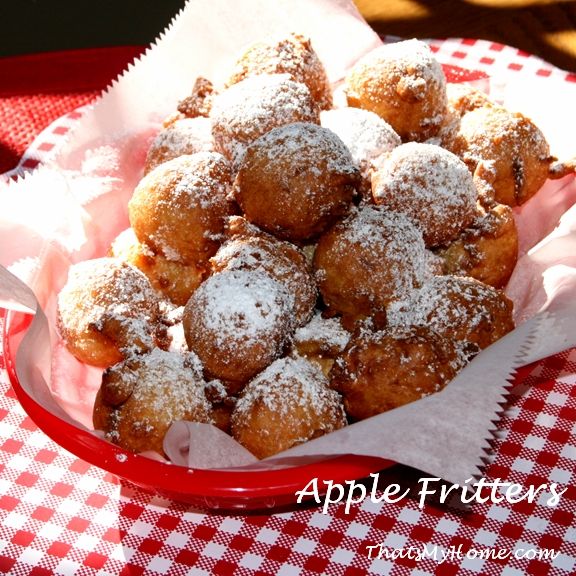 powdered sugar covered donuts in a red bowl on a checkered tablecloth