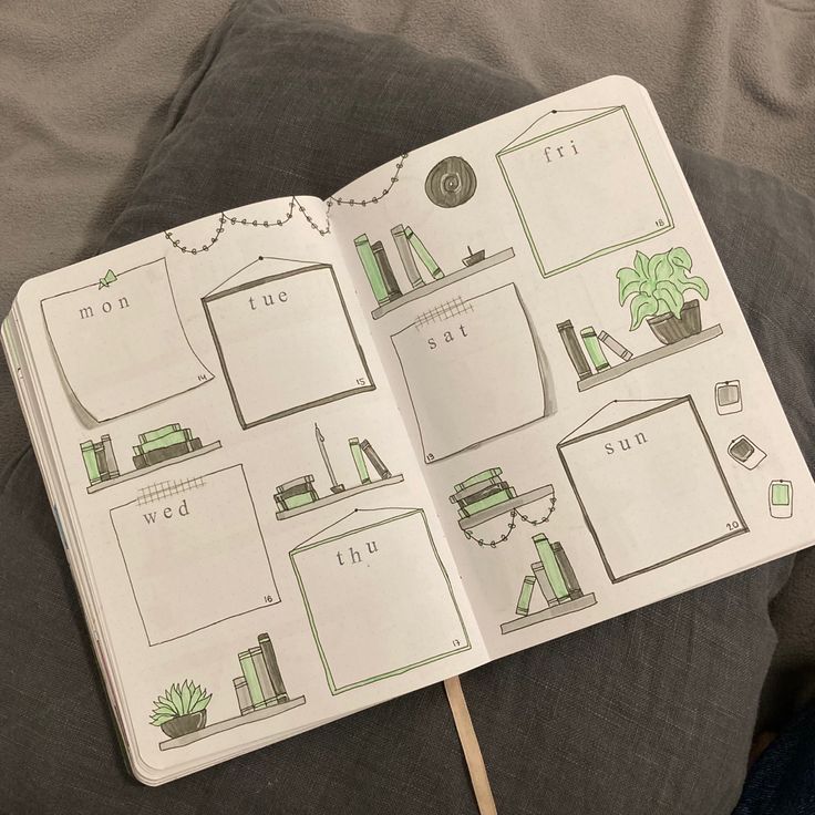 an open notebook with drawings on it sitting on a couch next to a plant and bookshelf