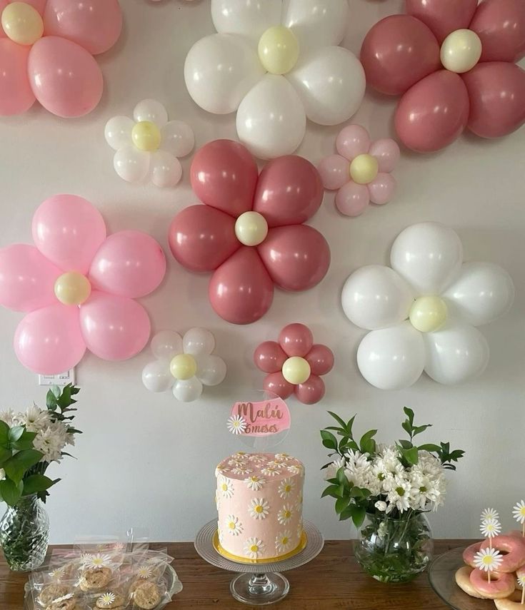 a table topped with a cake and lots of balloons