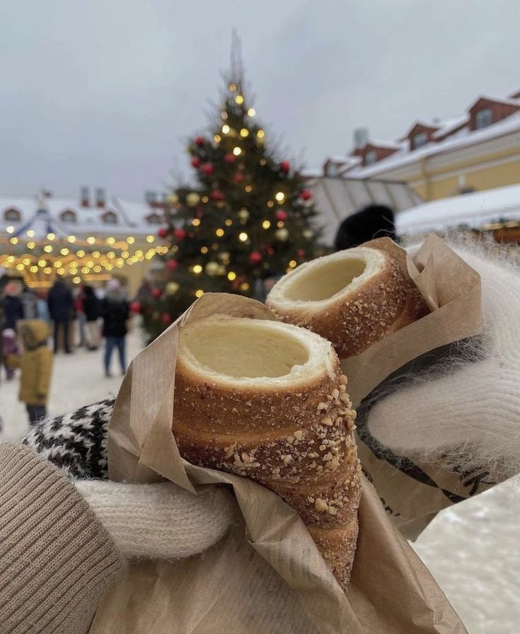 a person holding up some bread in front of a christmas tree