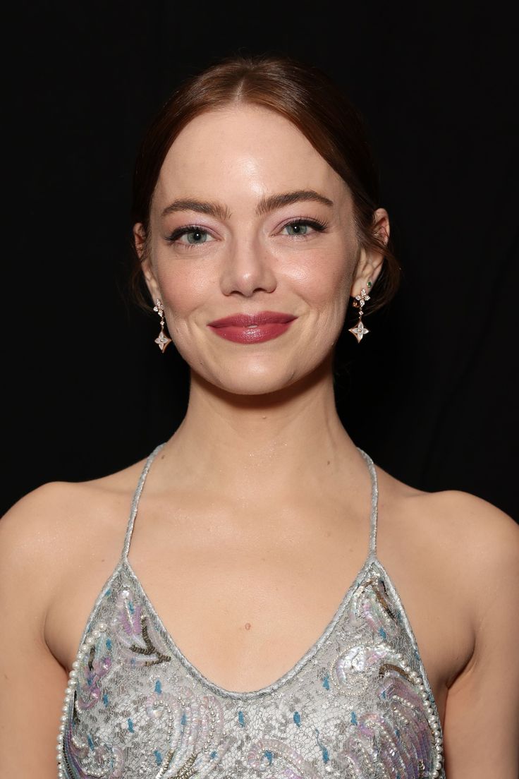 a woman in a silver dress smiling at the camera with her eyes closed and red lipstick on