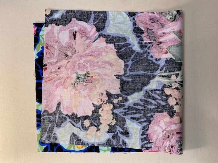 a square piece of fabric with pink flowers on black and blue floral print, hanging on a wall