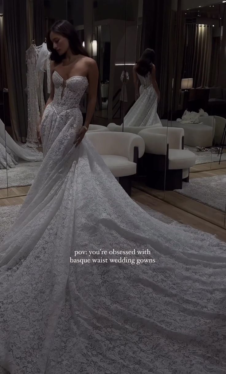 a woman standing in front of a mirror wearing a wedding dress