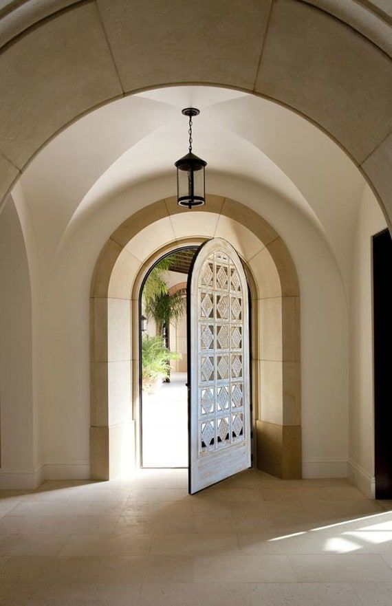 an arched doorway with a light fixture hanging from it's side and the door open