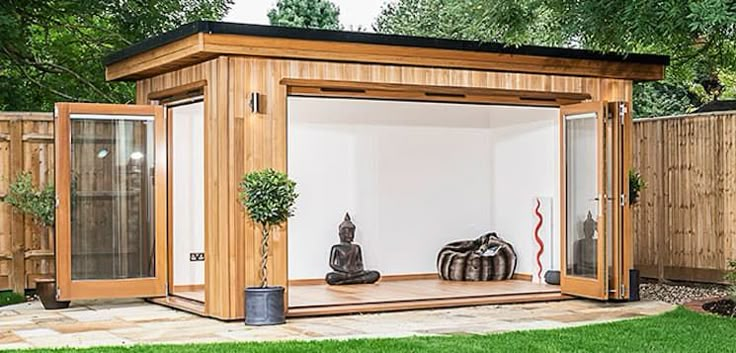 a small wooden structure in the middle of a yard with grass and trees around it