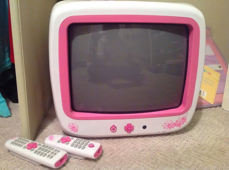 a pink and white tv sitting next to two remotes on the floor in front of a wall