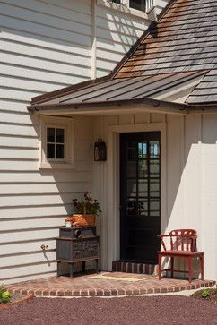 a white house with a black door and two red chairs