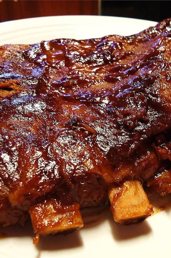 ribs and potatoes on a white plate with sauce