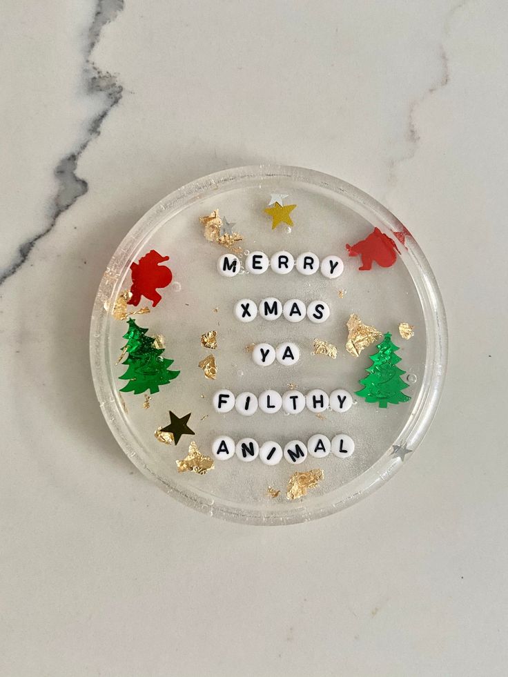 merry xmas ya filthy animal christmas ornament on a marble surface with gold, silver and red ornaments