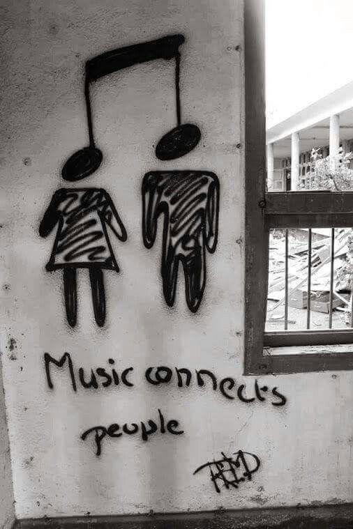 graffiti on the side of a building with music notes and people's faces painted on it