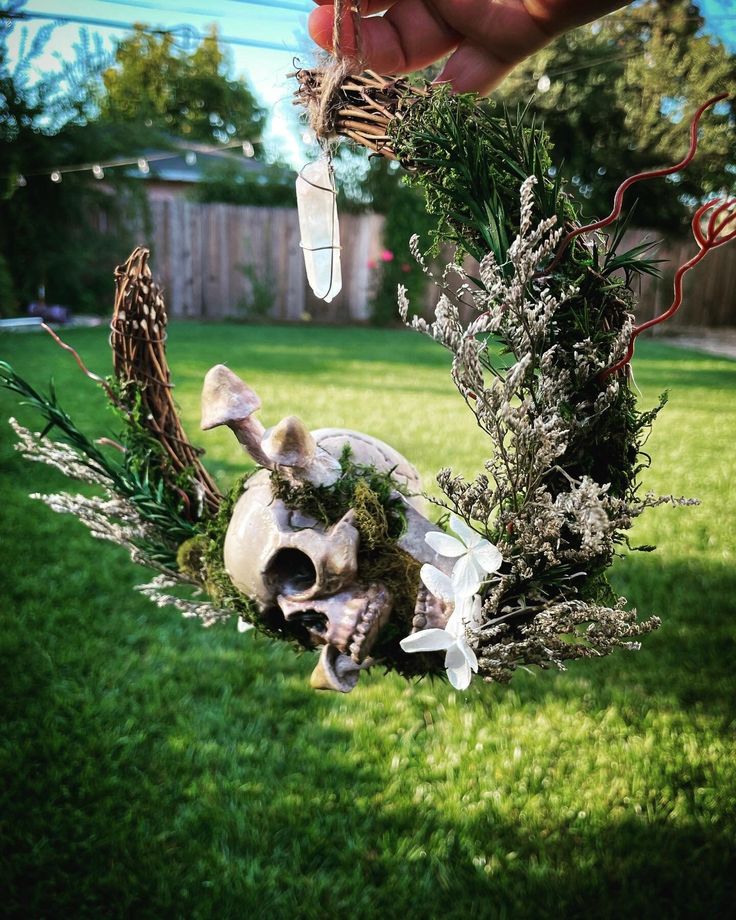 a person is holding a fake animal skull in the grass with other plants and flowers