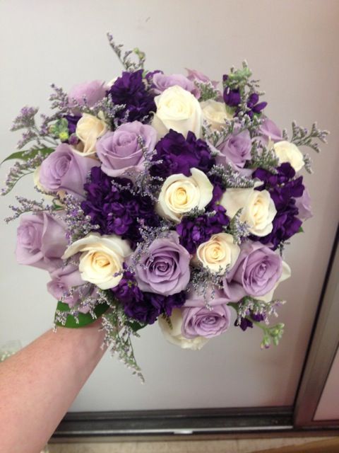 a bouquet of purple and white flowers in someone's hand