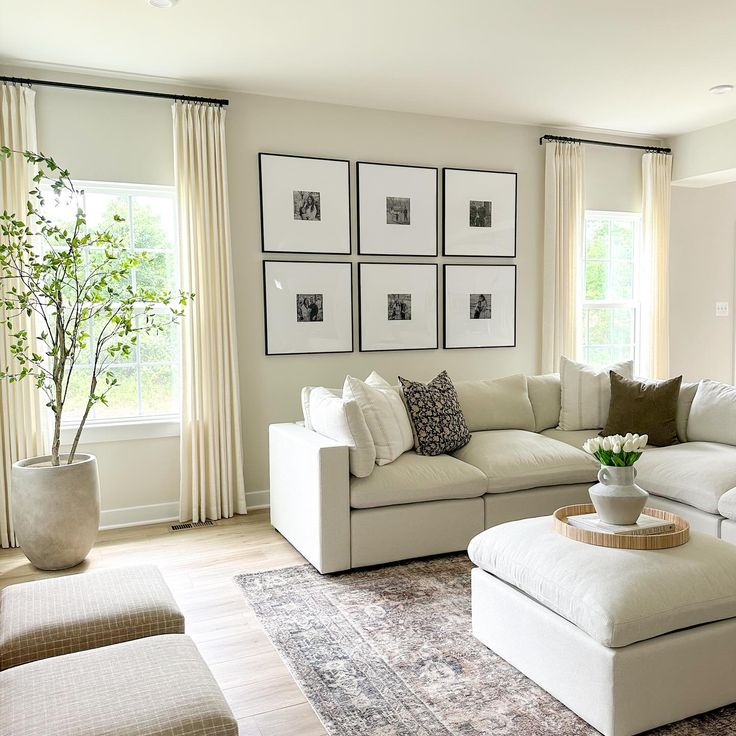 a living room with white furniture and pictures on the wall above it's couches