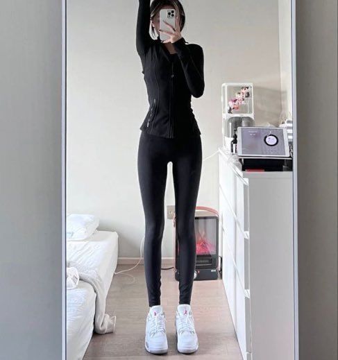 a woman taking a selfie in the mirror with her cell phone while wearing all black