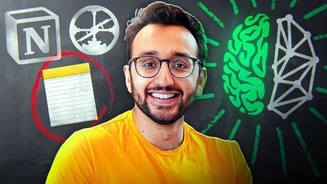 a man with glasses and yellow shirt in front of a blackboard that has various symbols on it