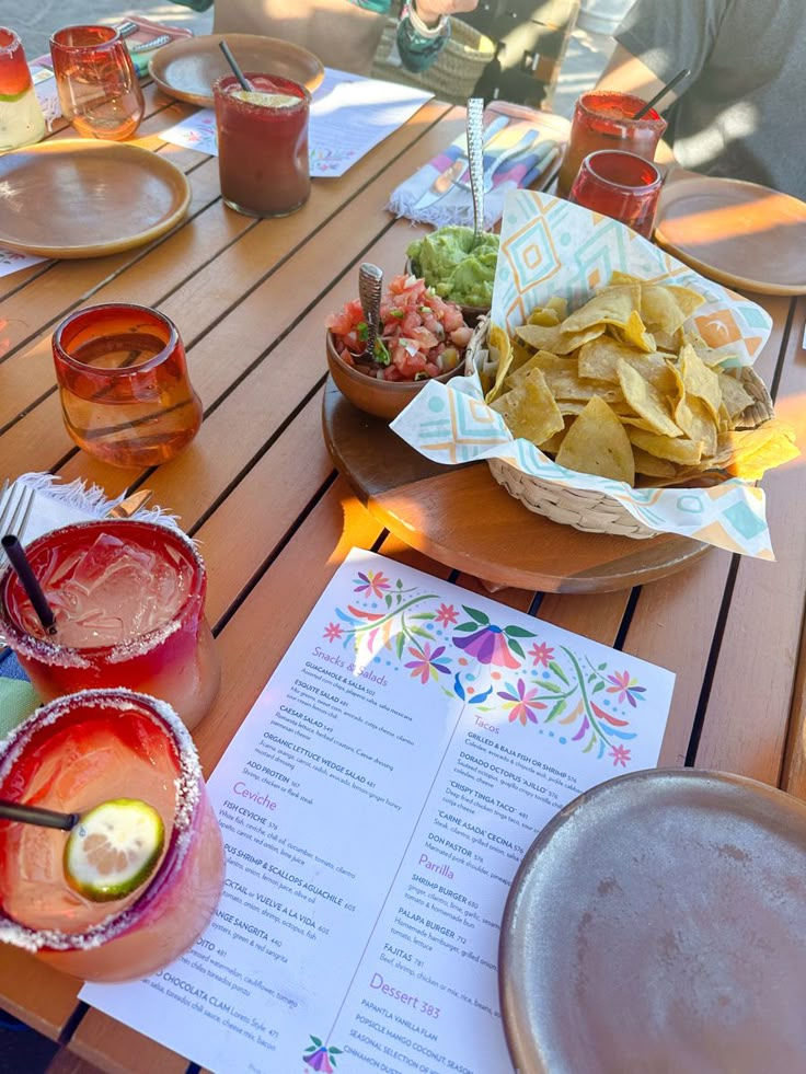 there are many drinks and food on the table at this outdoor restaurant that is ready to be eaten