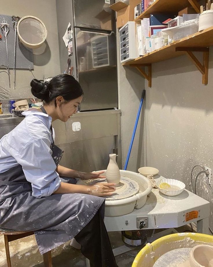 a woman is making pottery on a potter's wheel