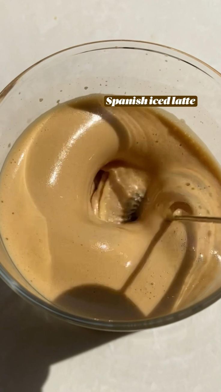 a glass bowl filled with liquid on top of a white countertop next to a spoon