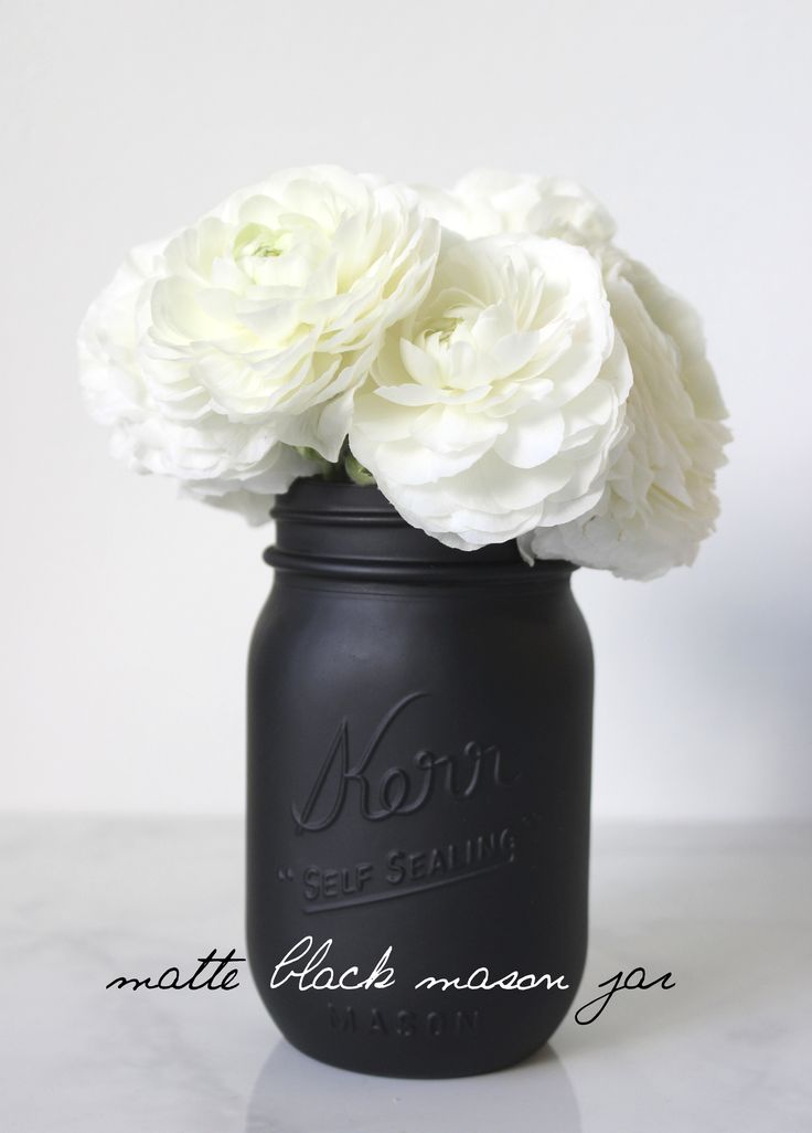 a black mason jar with white flowers in it