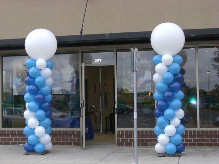 two tall blue and white balloons are in front of a building with glass doors on both sides