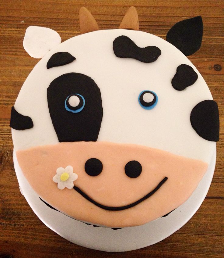 a cake decorated with a cow's face on top of a wooden table