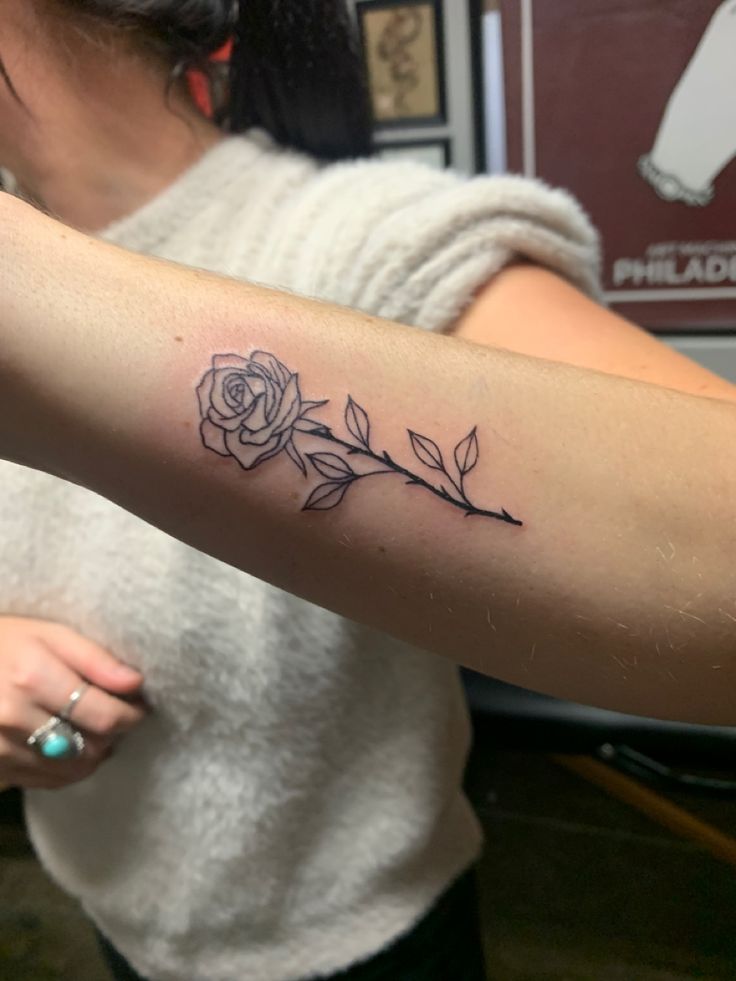 a woman with a rose tattoo on her arm