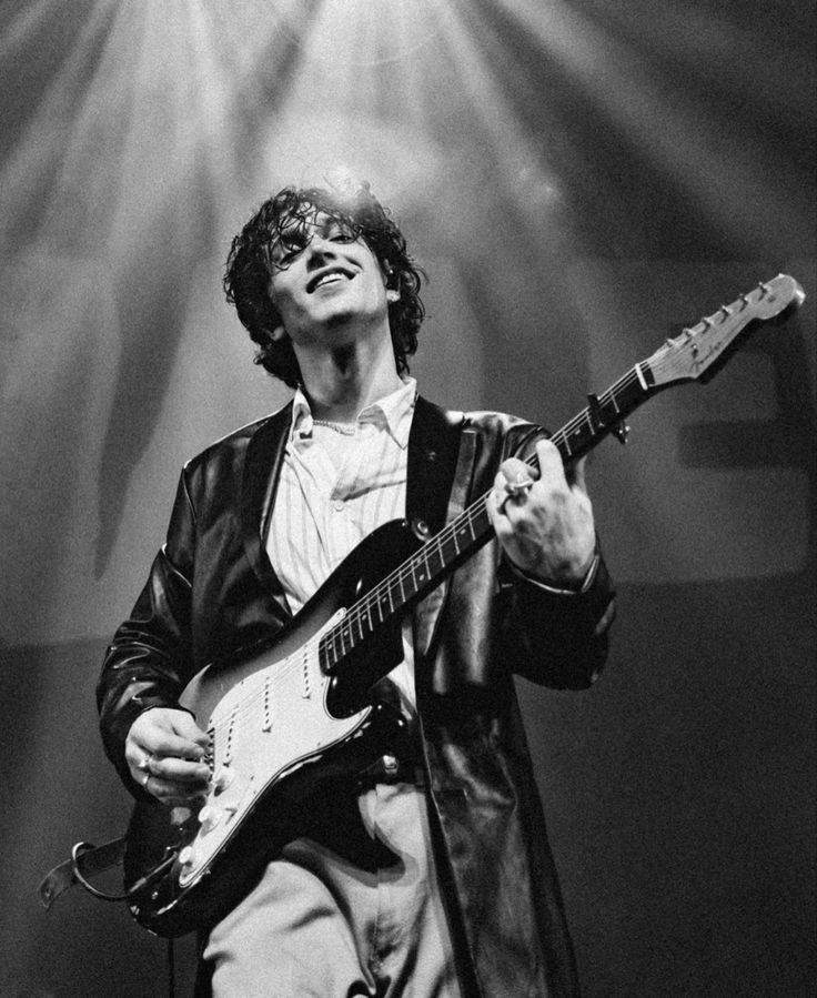 black and white photograph of a man playing an electric guitar in front of spotlights