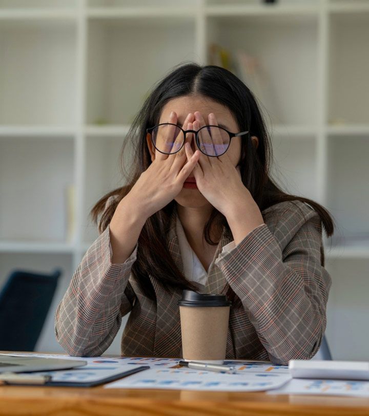 a woman sitting at a desk covering her eyes