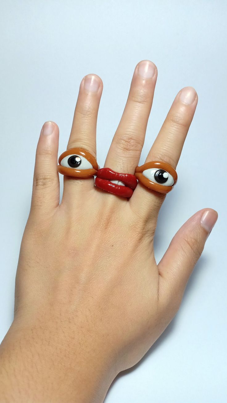 a woman's hand with two fake eyes on it and a red ribbon around the ring