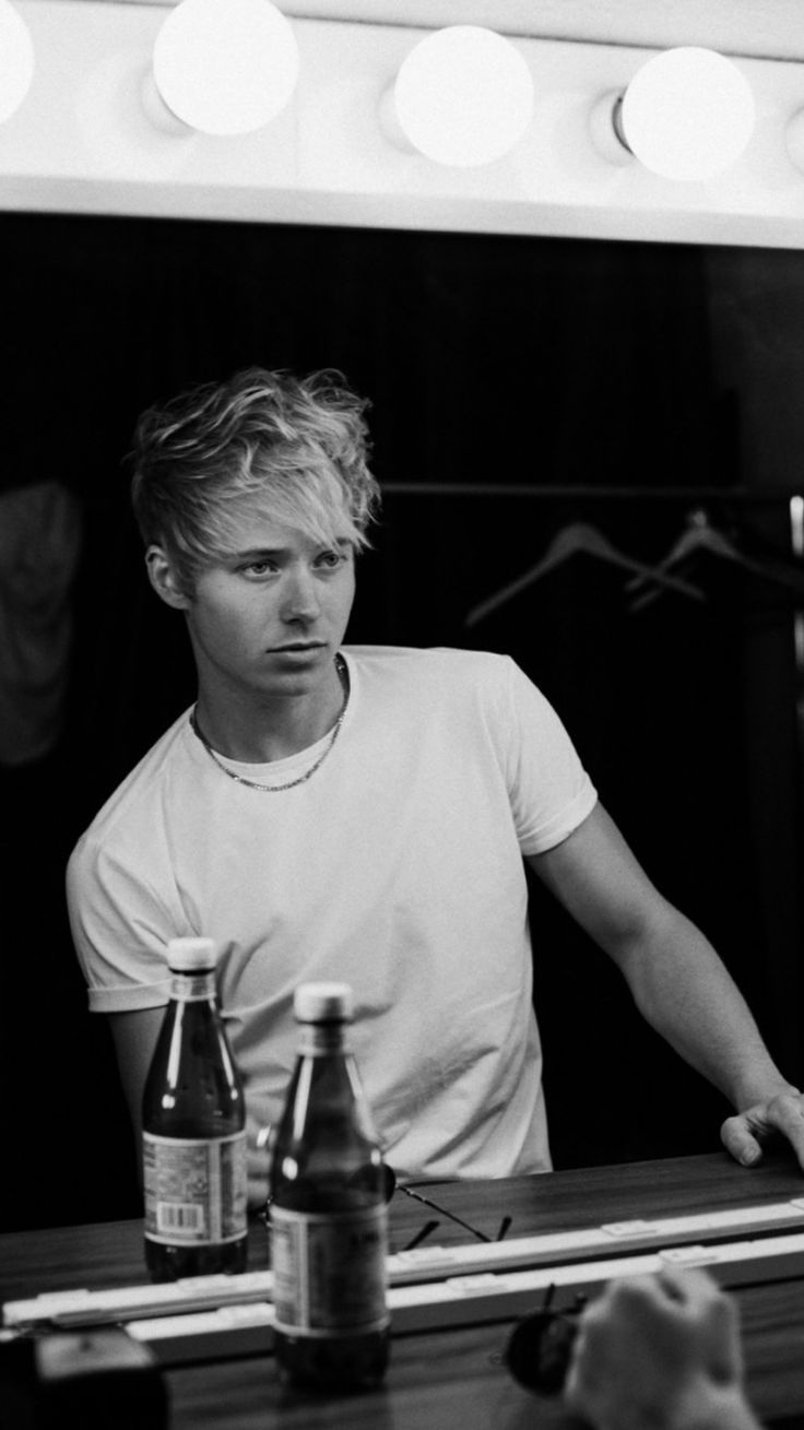 a man standing in front of a mirror next to bottles