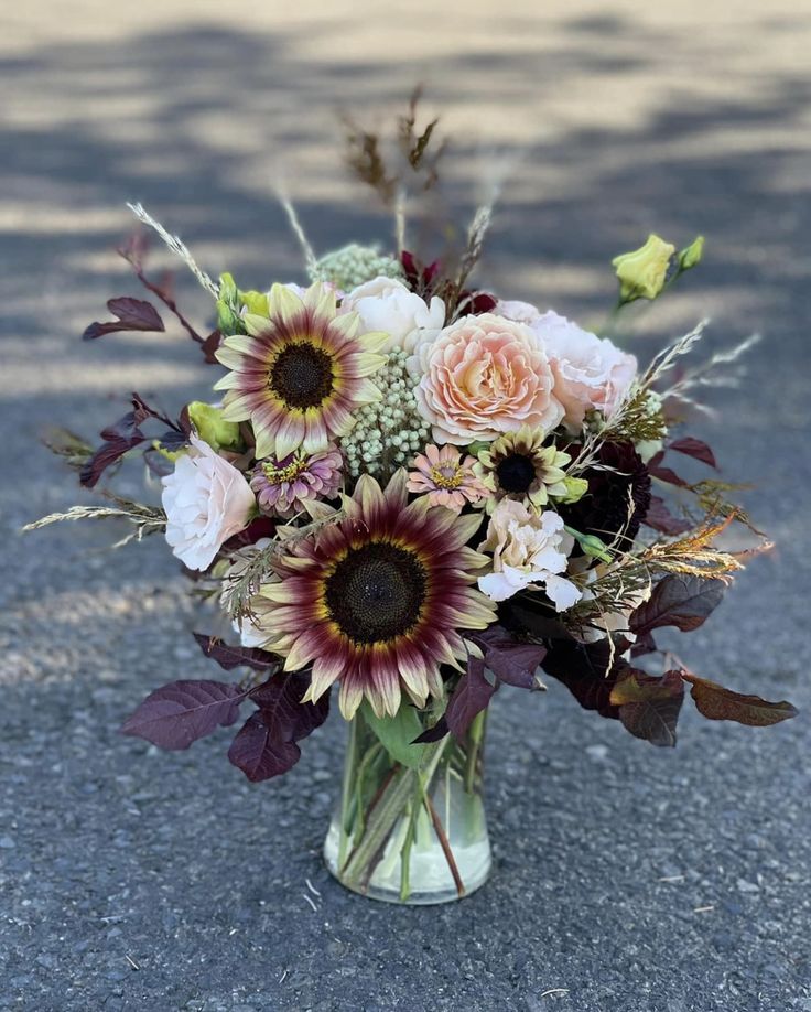 a vase filled with lots of flowers sitting on the ground