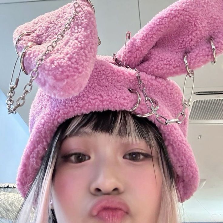 a girl wearing a pink bunny ears hat with chains on it's head and nose