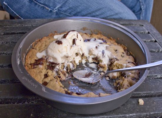 a pan filled with ice cream sitting on top of a wooden table next to a person