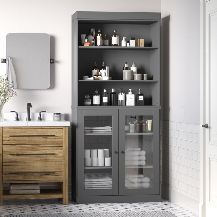 a bathroom with gray cabinets and white towels on the counter top, along with toiletries