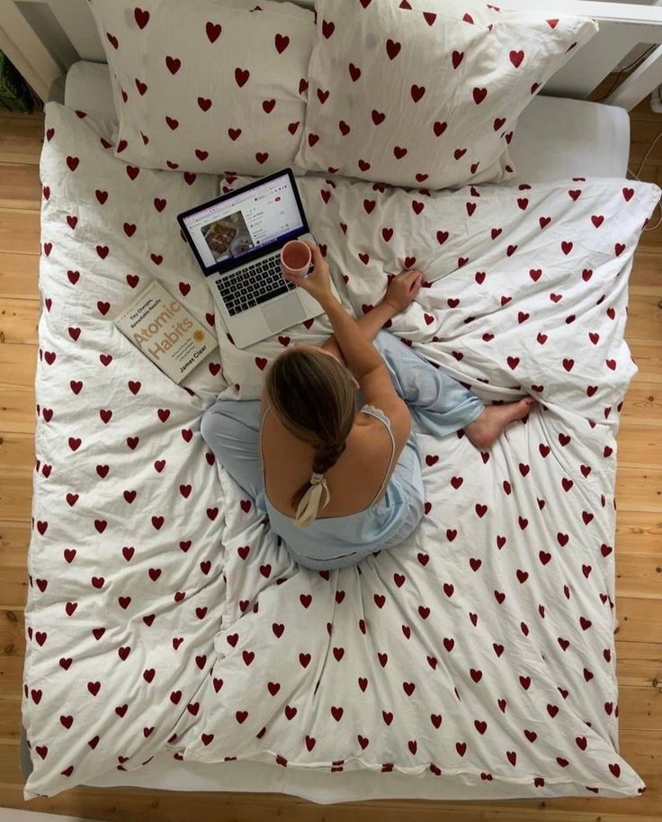 a woman sitting on a bed using a laptop computer