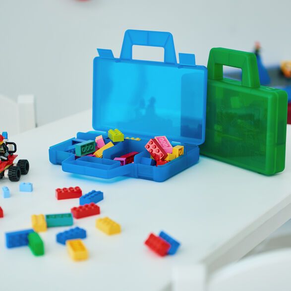 legos are scattered around a plastic toolbox and toy cars on a table top