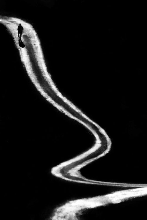 a black and white photo of a person riding a snowboard down a hill in the dark