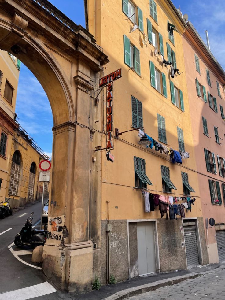 an arch in the middle of a street with clothes hanging out to dry on it