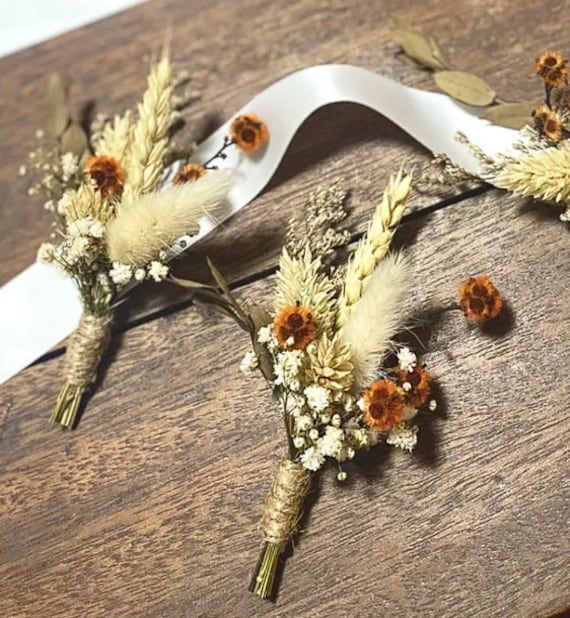 three dried flowers are placed on top of a wooden table with a white ribbon around them