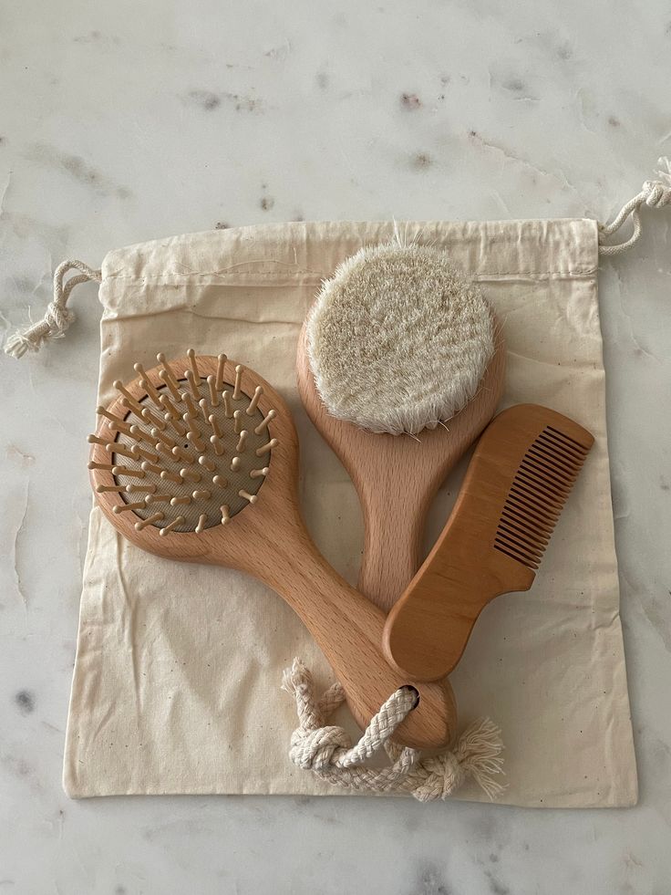 three wooden brush and combs sitting on top of a white cloth covered placemat