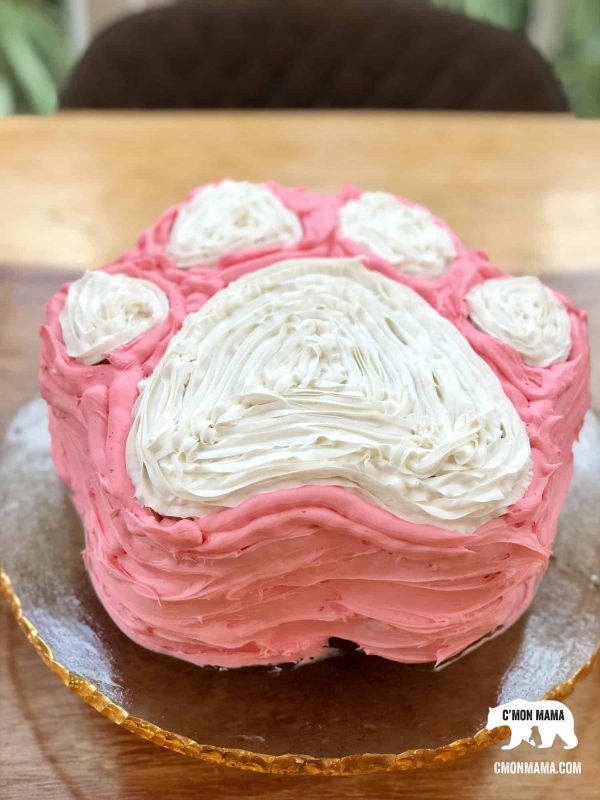 a pink and white frosted cake sitting on top of a wooden table