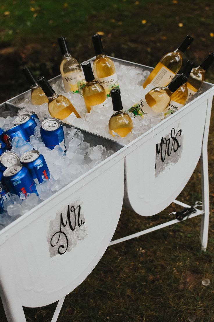 a cooler filled with lots of bottles of wine and glasses on top of ice cubes